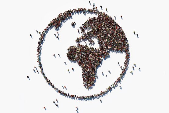 große Gruppe von Menschen formiert sich zu einer Weltkugel